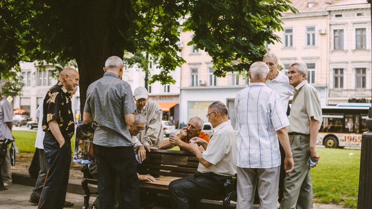people standing and sitting on bench during daytime